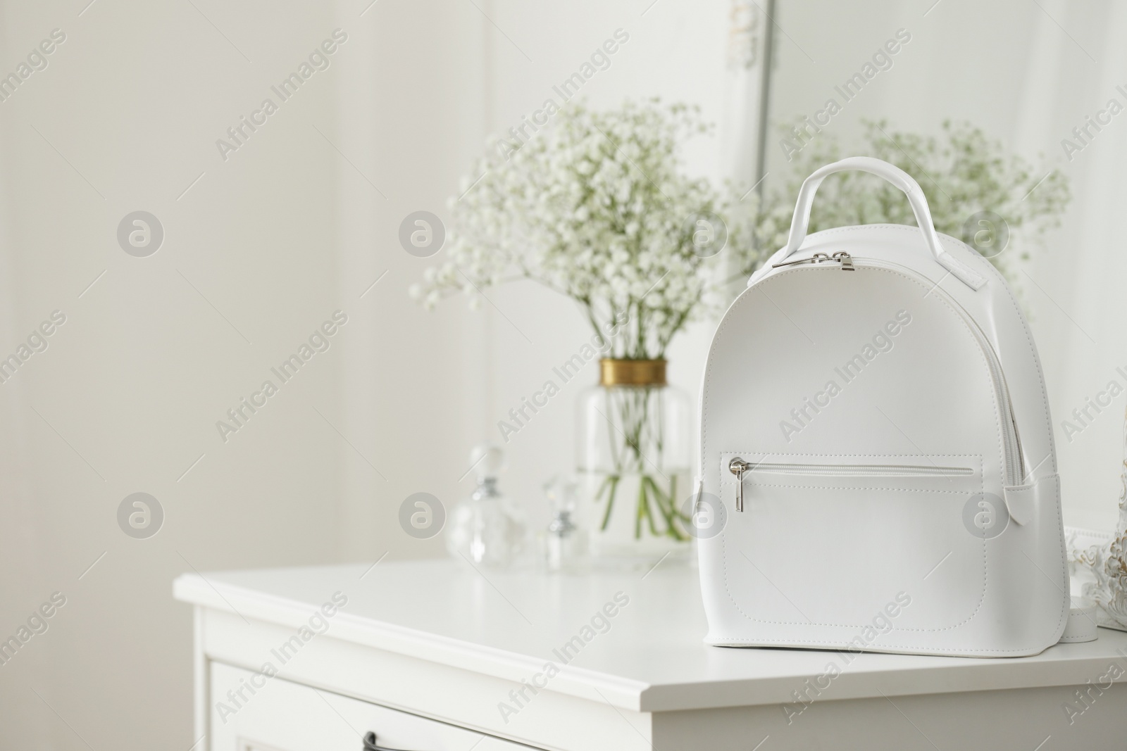 Photo of Stylish white backpack on chest of drawers indoors, space for text