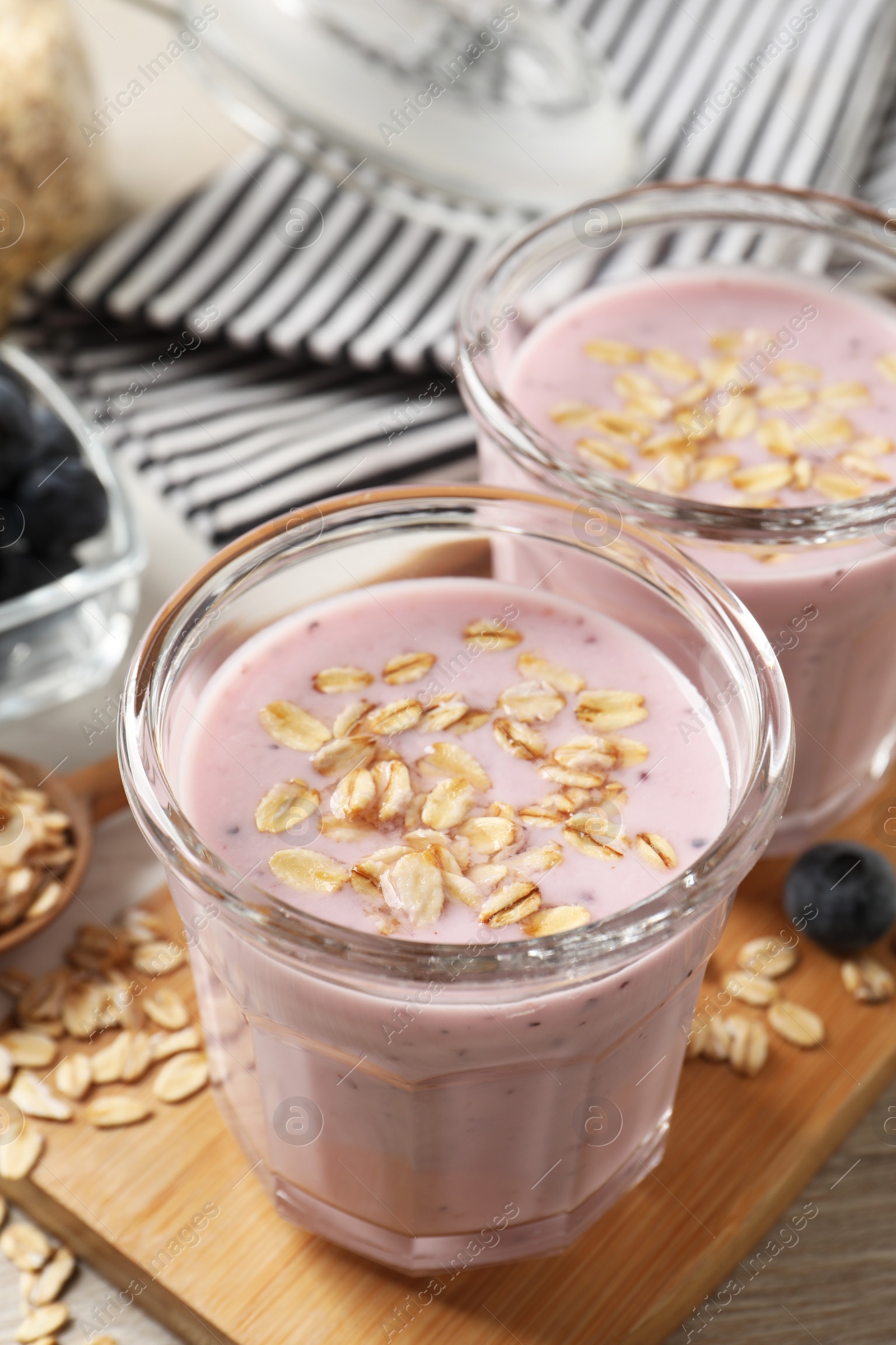 Photo of Glasses of tasty blueberry smoothie with oatmeal on table