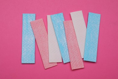 Photo of Sticks of tasty chewing gum on bright pink background, flat lay