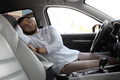 Photo of Tired man sleeping in his modern car