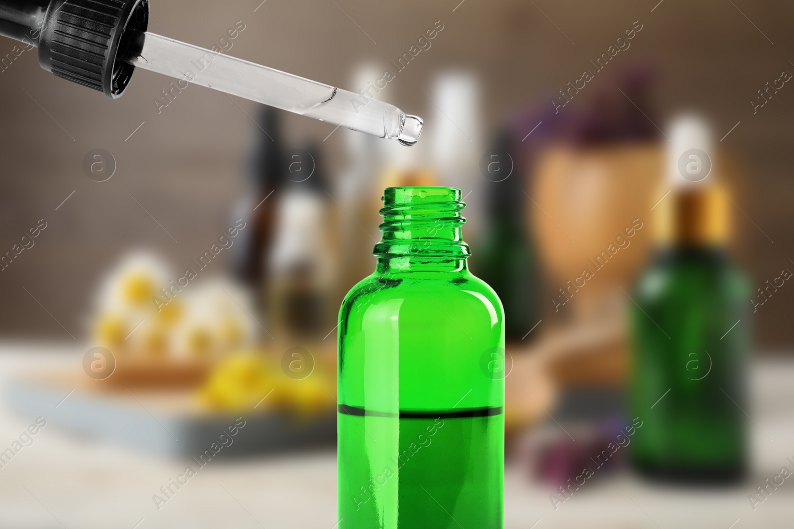 Image of Little bottle with essential oil and dropper against blurred background 