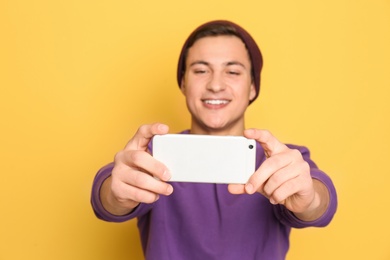 Young handsome man taking selfie against color background