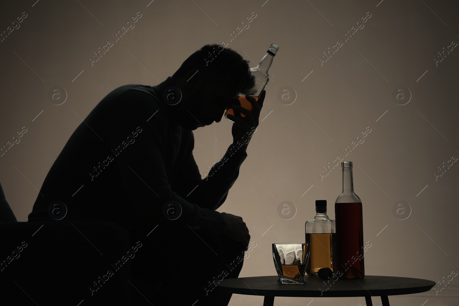 Photo of Silhouette of addicted man with alcoholic drink indoors