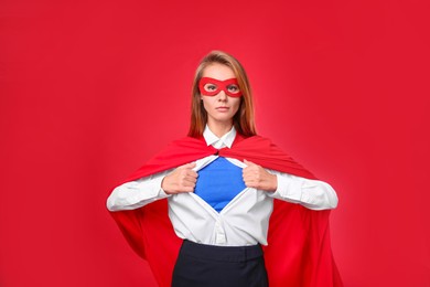 Photo of Confident businesswoman wearing superhero costume under suit on red background