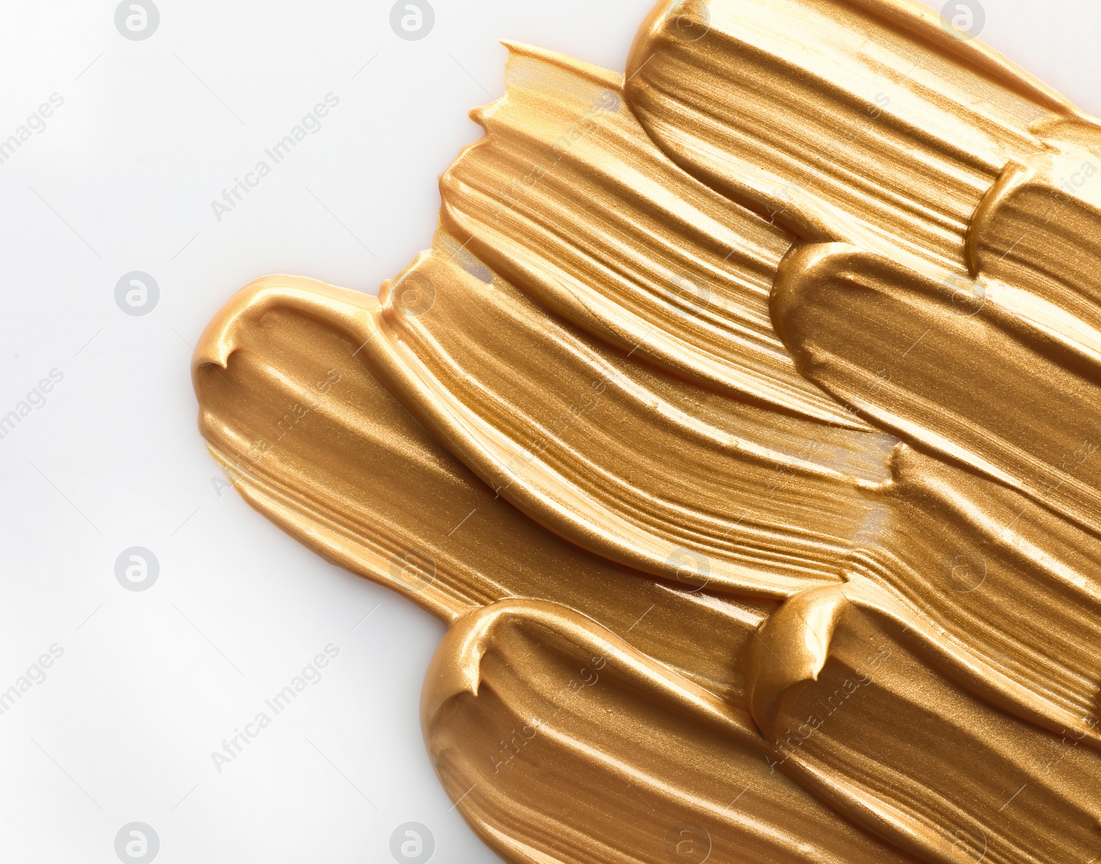 Photo of Strokes of gold paint isolated on white, top view