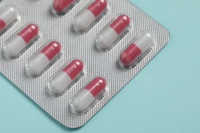 Photo of Pills in blister on turquoise background, closeup