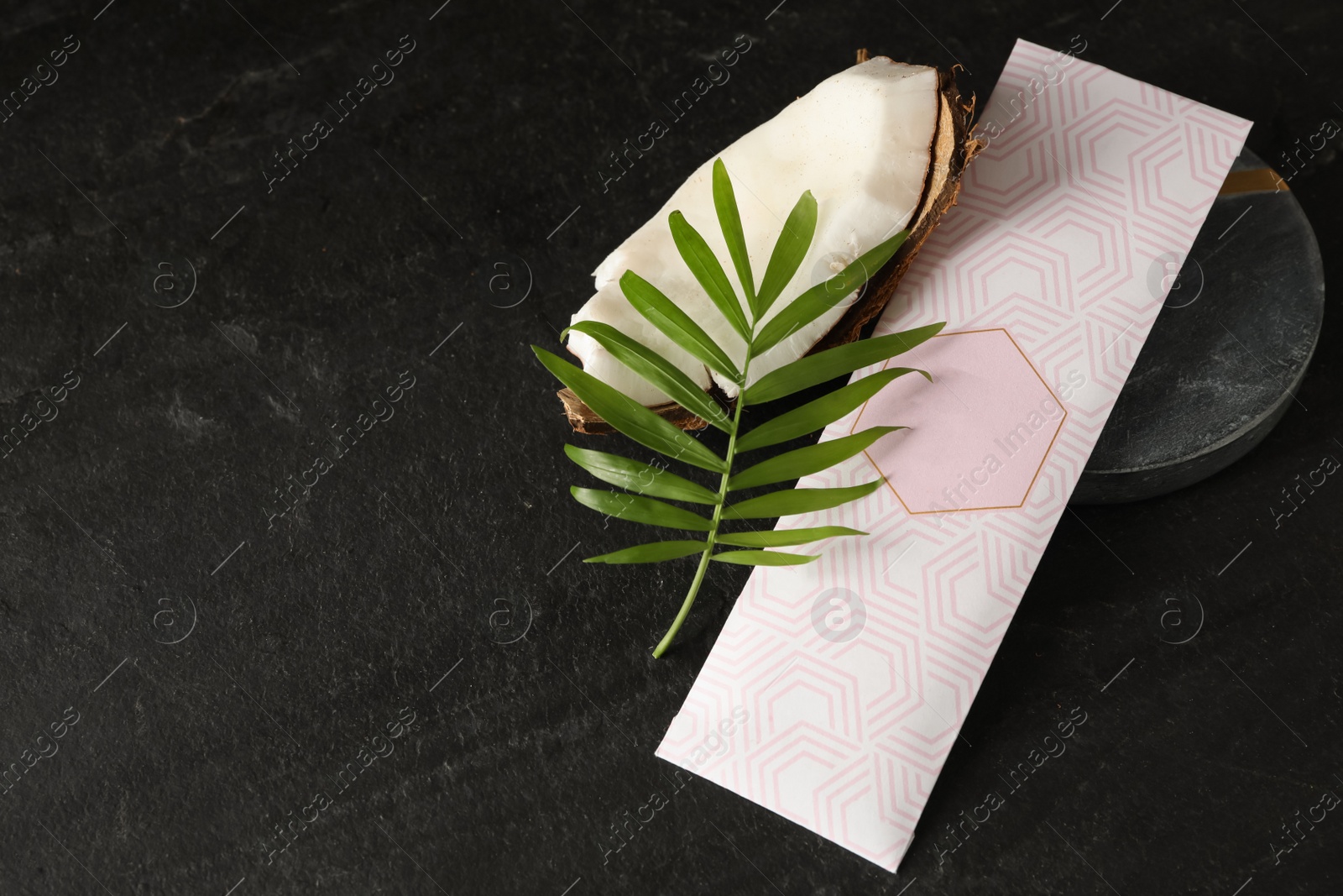 Photo of Scented sachet, green leaf and piece of coconut on black table, above view. Space for text