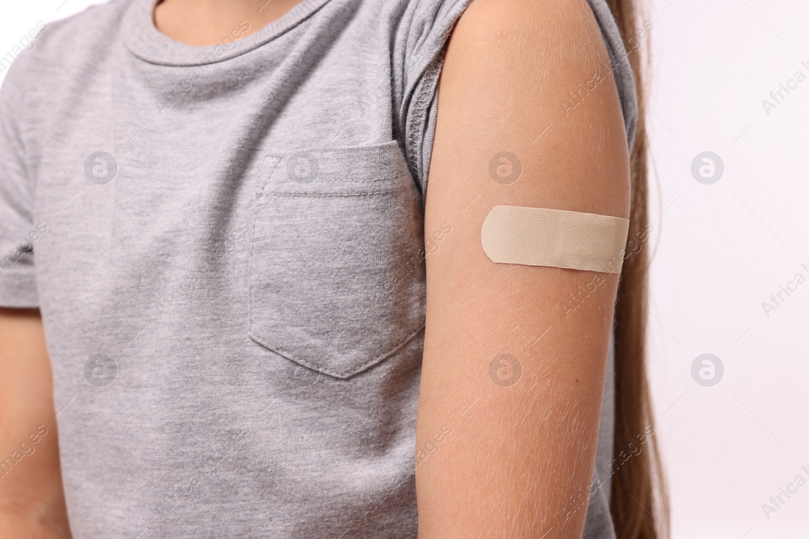 Photo of Girl with sticking plaster on arm after vaccination against white background, closeup