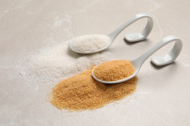 Photo of Spoons with white and brown sugar on light marble table, space for text