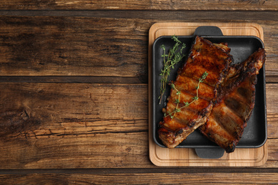 Photo of Tasty grilled ribs on wooden table, top view. Space for text