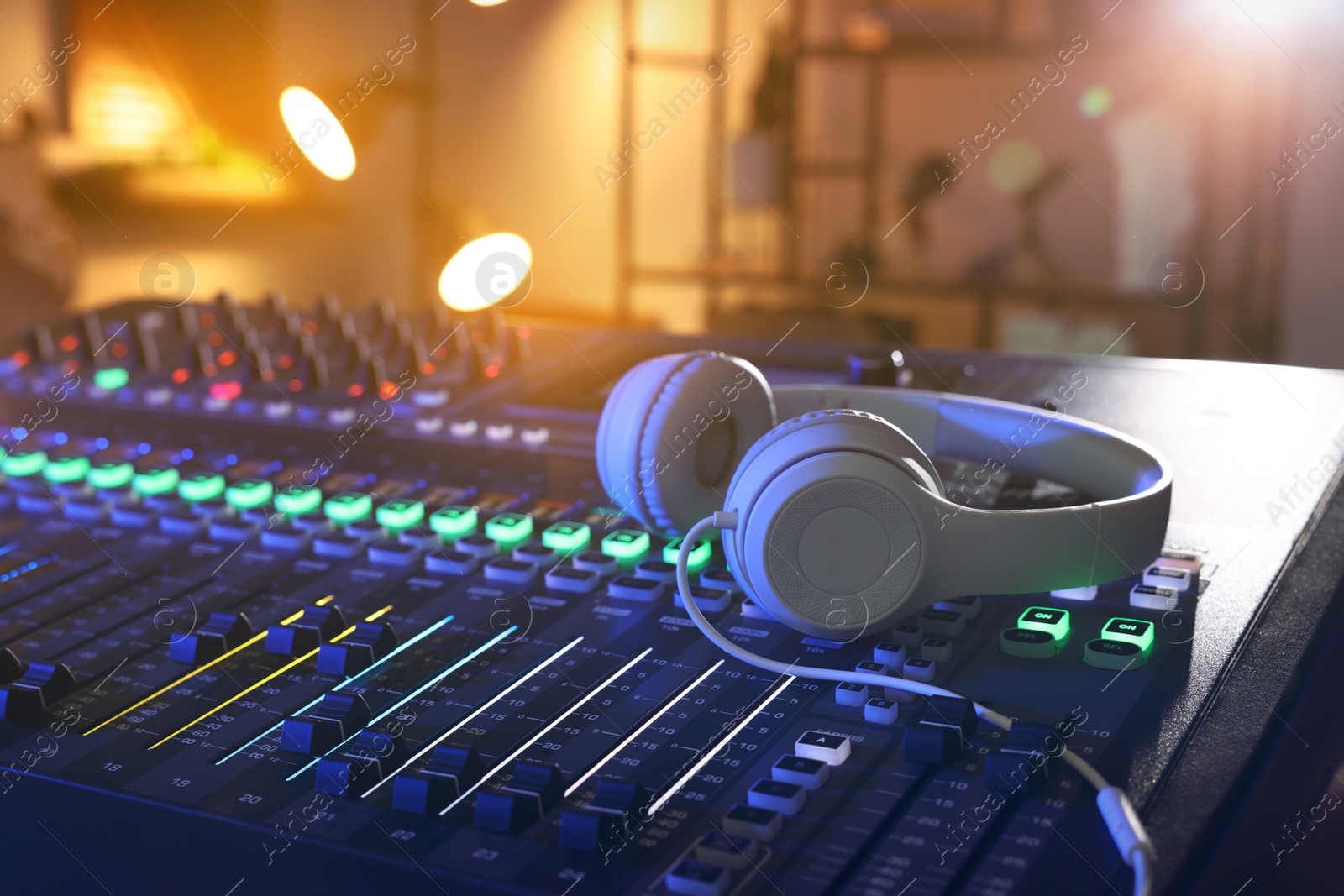 Photo of Professional mixing console with headphones in radio studio, closeup