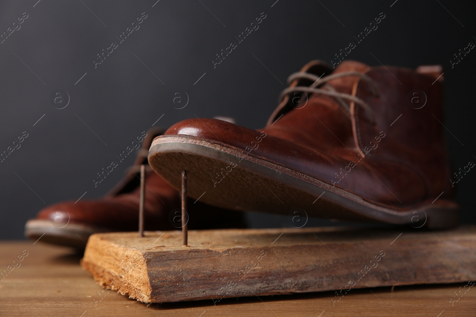 Photo of Metal nails in wooden plank and shoes on table