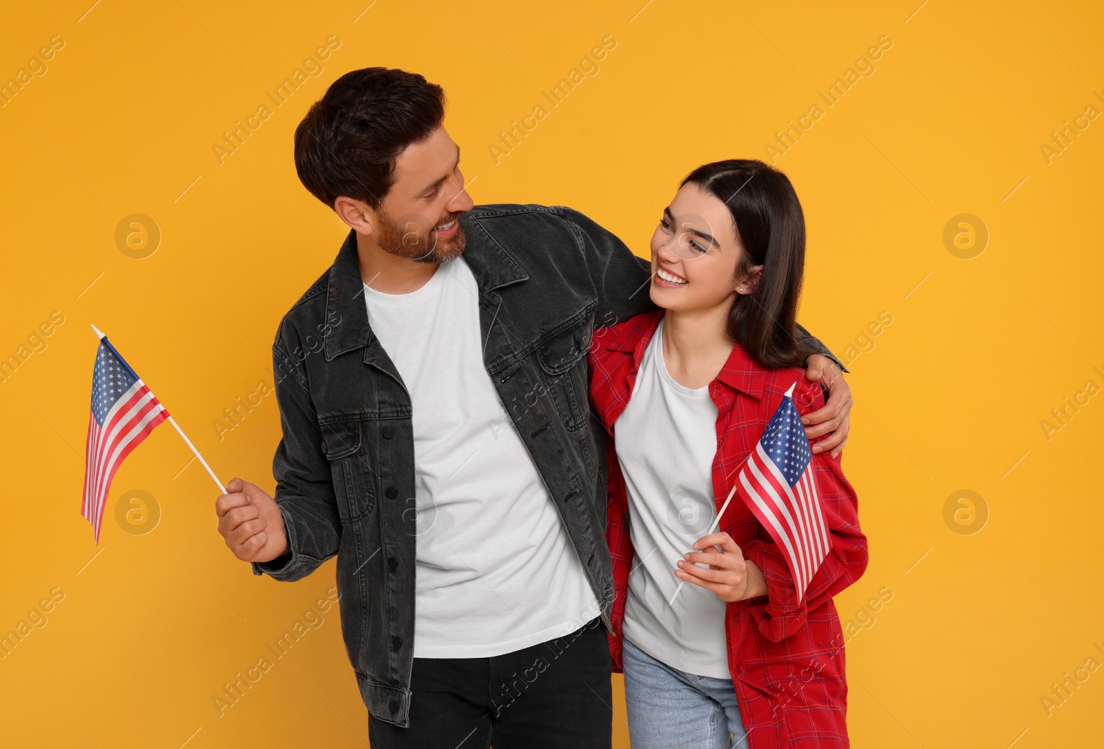 Photo of 4th of July - Independence Day of USA. Happy man and his daughter with American flags on yellow background