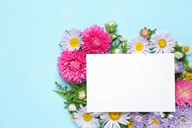 Flat lay composition with beautiful aster flowers and blank card on light blue background. Space for text