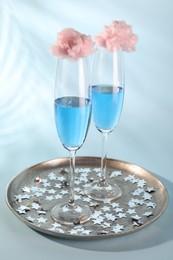 Photo of Cotton candy cocktails in glasses and confetti on light blue background