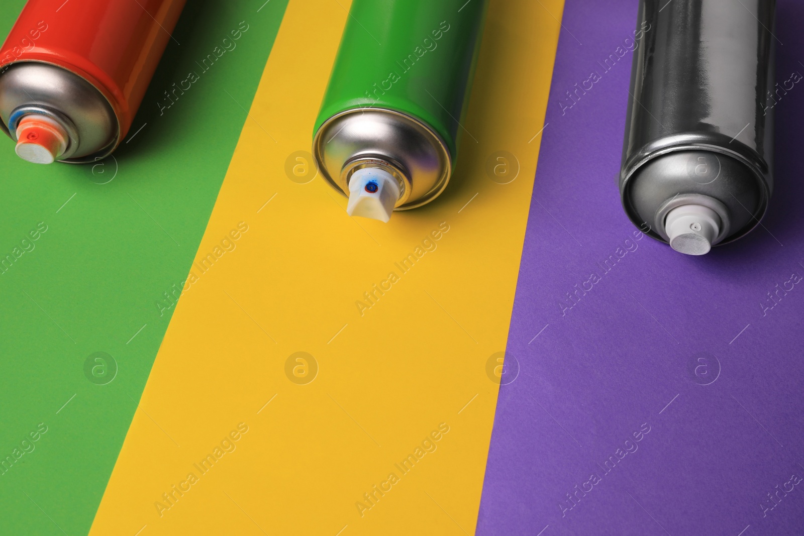 Photo of Cans of different spray paints on color background, space for text. Graffiti supplies