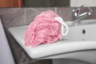 Pink shower puff on washbasin in bathroom, closeup