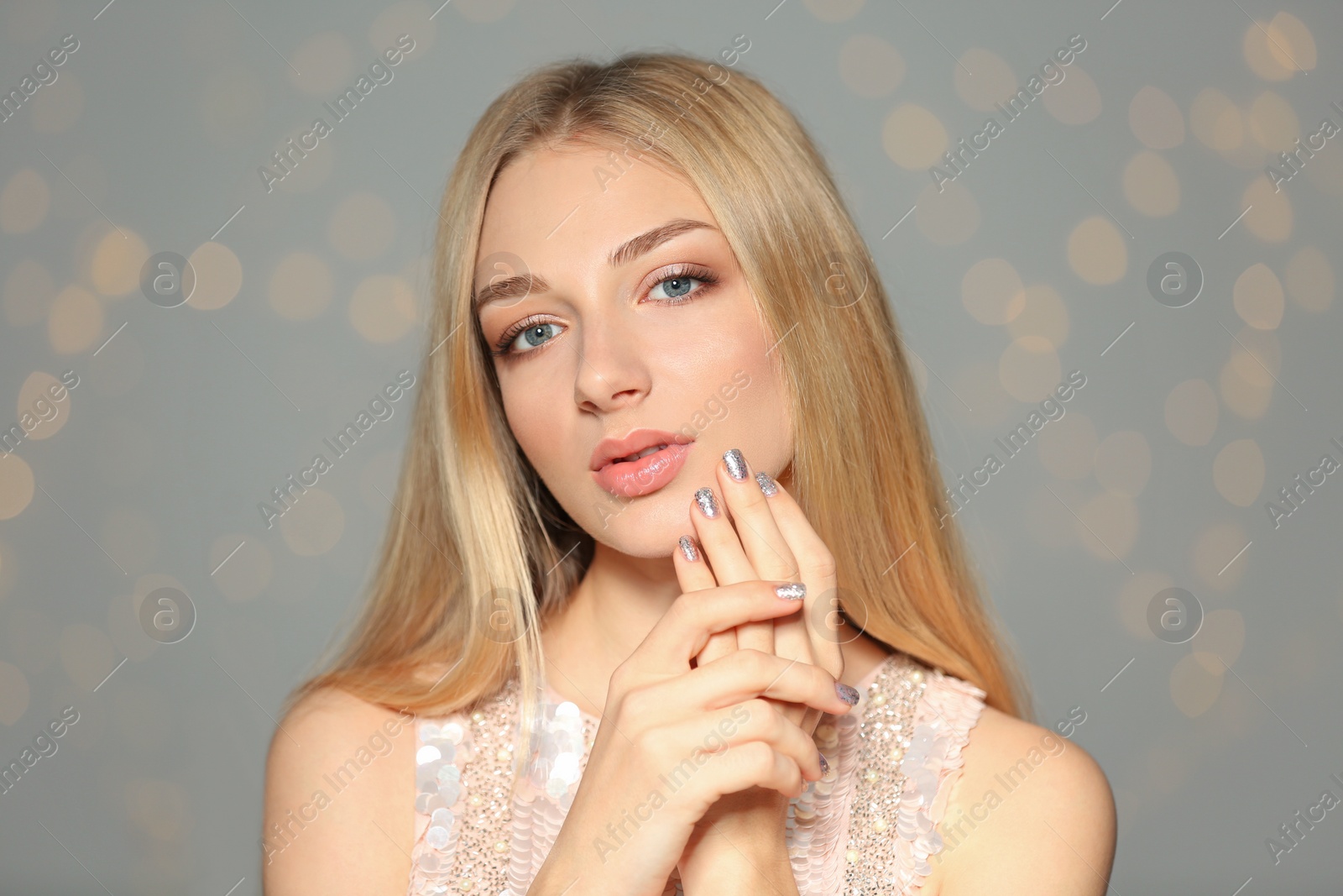 Photo of Portrait of beautiful young woman with shiny manicure on blurred background. Nail polish trends