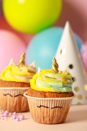 Photo of Cute sweet unicorn cupcakes on beige table, closeup. Space for text