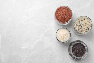 Photo of Brown and polished rice on grey marble table, flat lay. Space for text