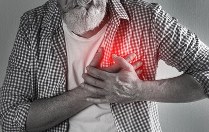 Image of Mature man having heart attack on light background, closeup