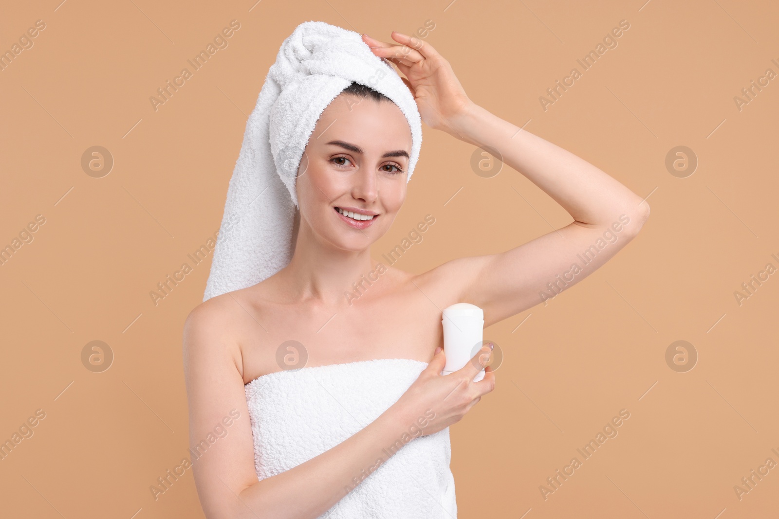 Photo of Beautiful woman applying deodorant on beige background