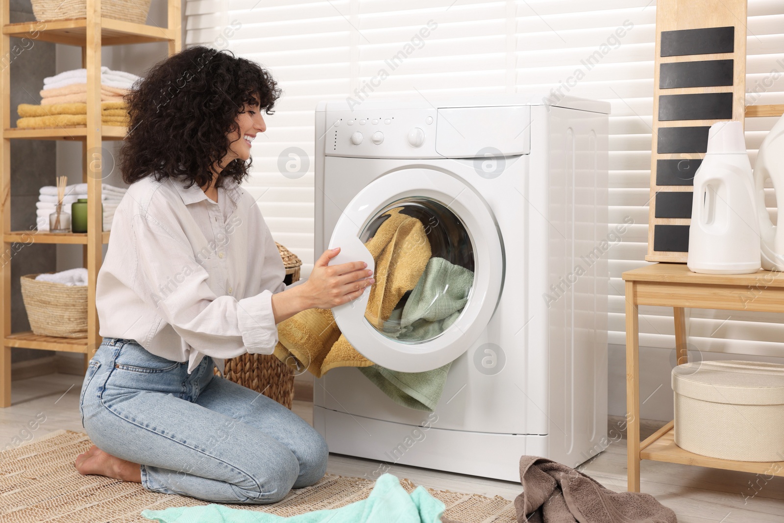 Photo of Woman putting laundry into washing machine indoors