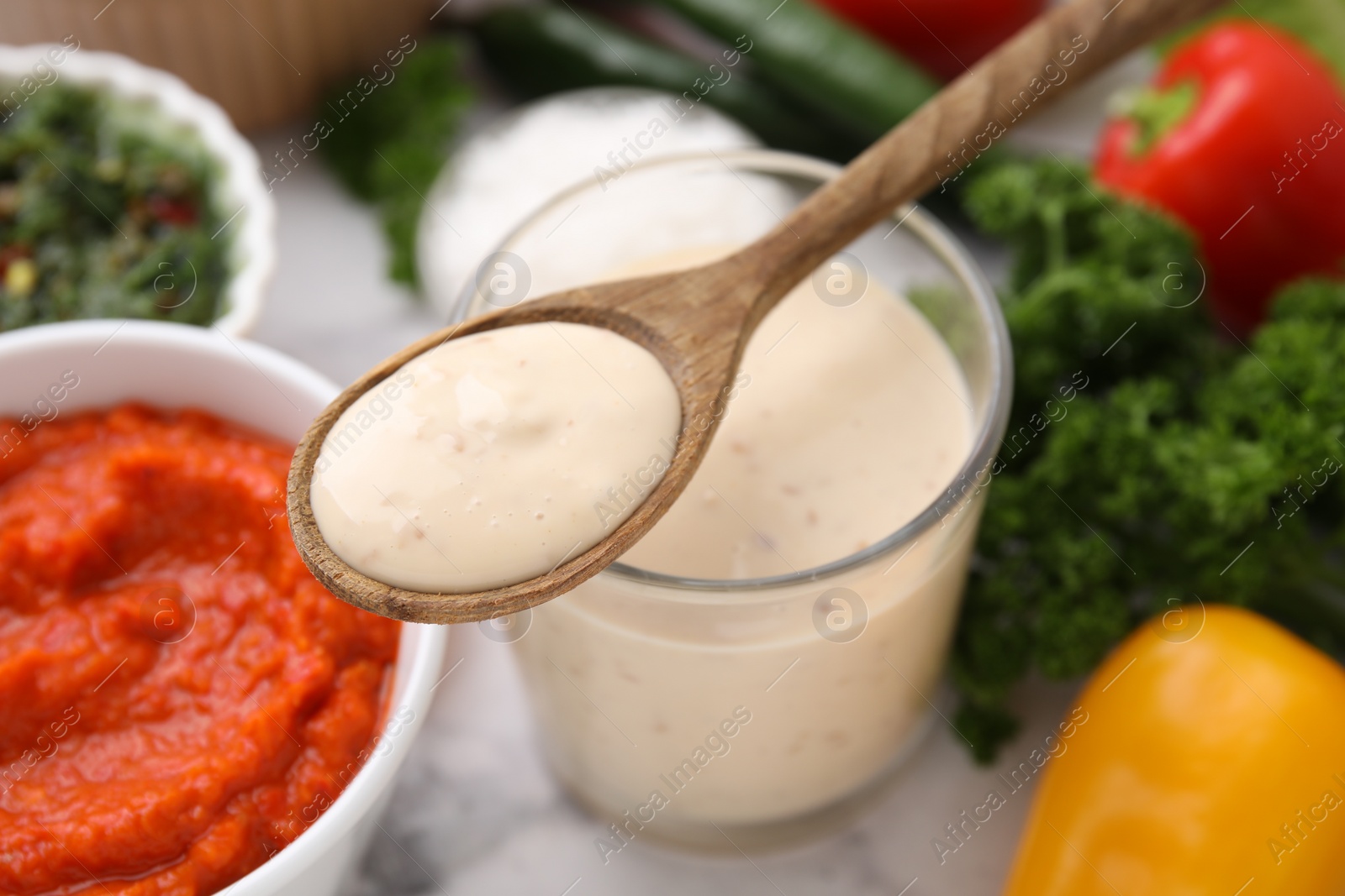 Photo of Spoon with fresh marinade over table, closeup