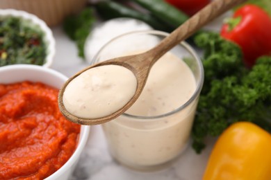 Photo of Spoon with fresh marinade over table, closeup