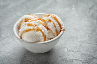 Tasty ice cream with caramel sauce in bowl on table