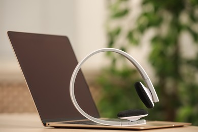 Photo of Modern headphones and laptop on table indoors