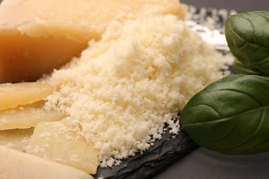 Photo of Delicious grated parmesan cheese on black slate board, closeup