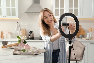 Photo of Blogger preparing for video recording in kitchen at home. Using smartphone and ring lamp