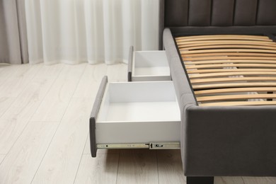 Storage drawers for bedding under modern bed in room. Space for text