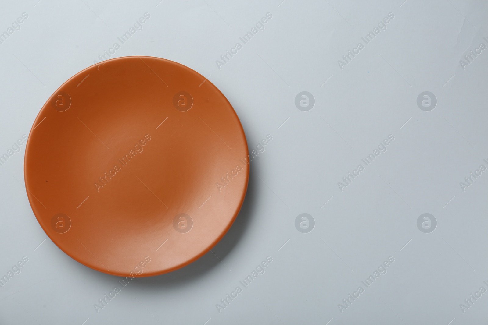 Photo of Clean orange plate on light grey background, top view. Space for text