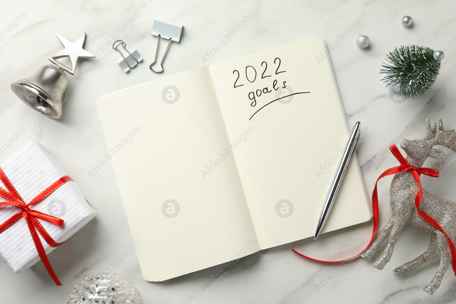 Photo of Inscription 2022 Goals written in planner and Christmas decor on white marble background, flat lay. New Year aims