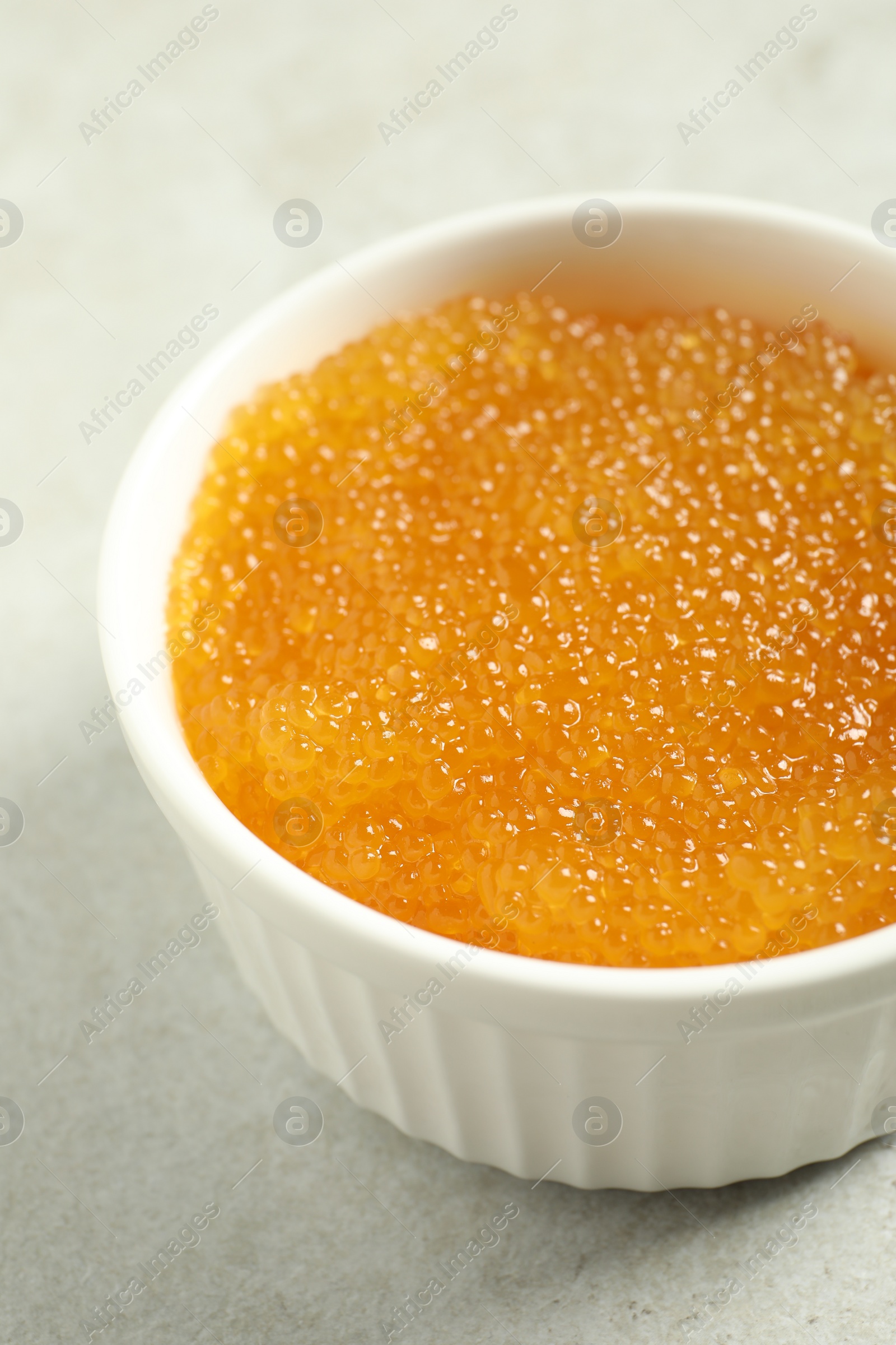 Photo of Fresh pike caviar in bowl on light grey table, closeup