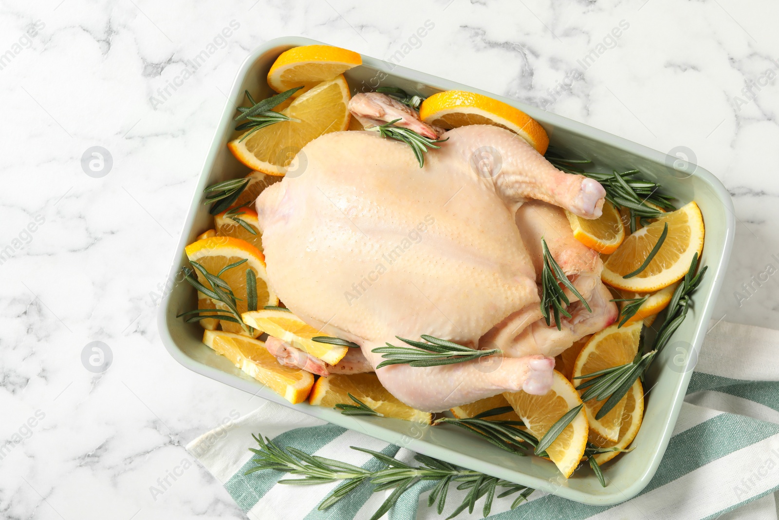 Photo of Flat lay composition with chicken, orange slices, rosemary and kitchen towel on white marble table