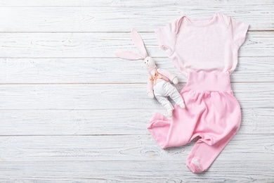 Photo of Stylish baby clothes and toy on wooden background. Space for text