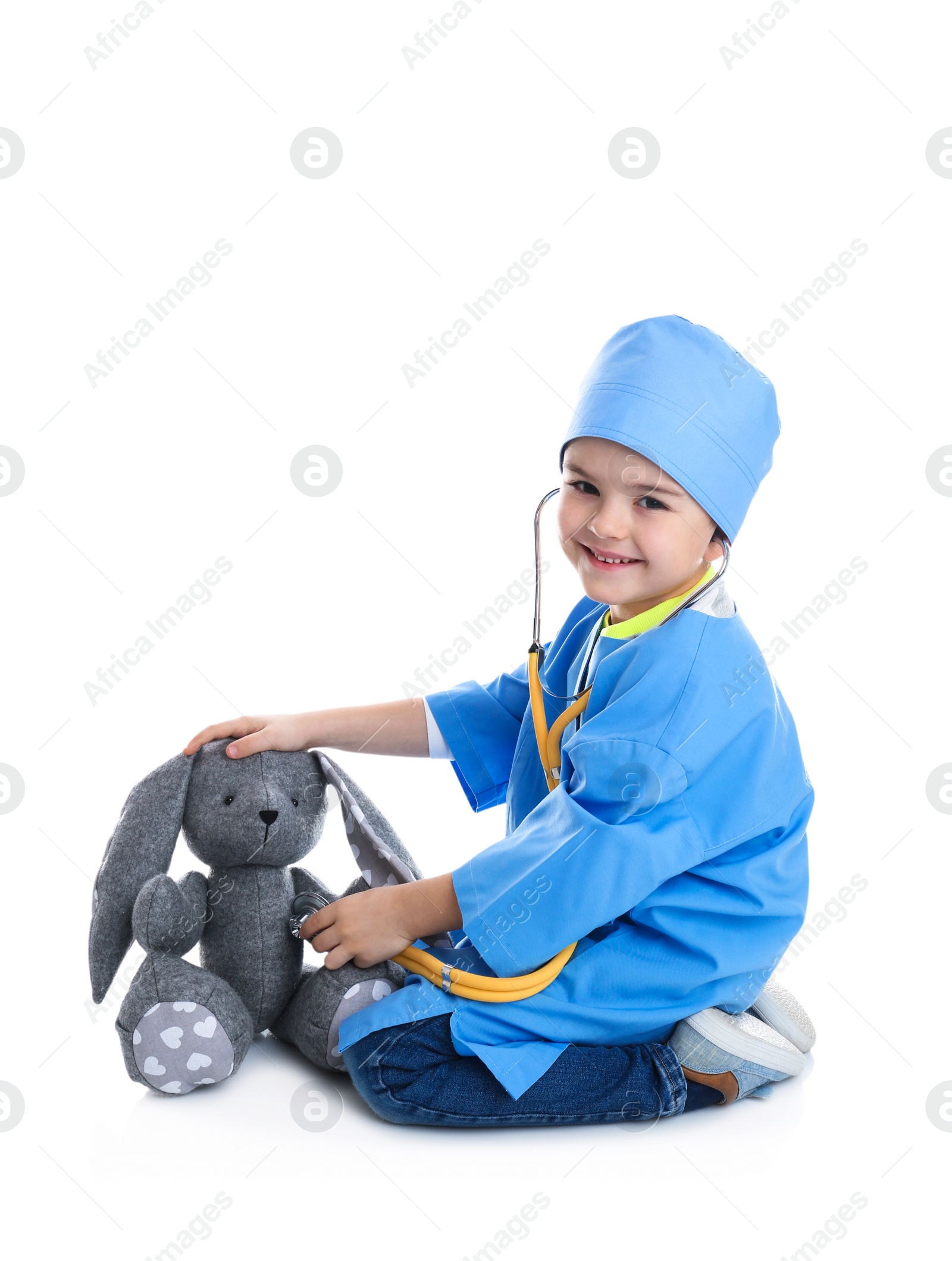 Photo of Cute child playing doctor with stuffed toy on white background