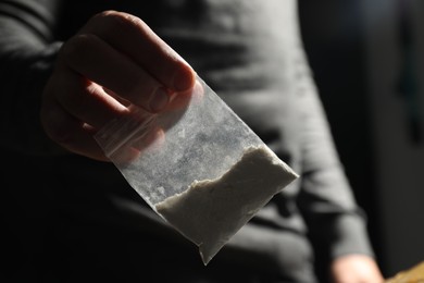 Photo of Drug addiction. Man giving plastic bag with cocaine on dark background, closeup