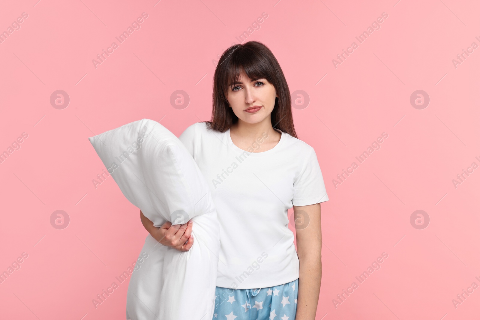 Photo of Woman in pyjama holding pillow on pink background