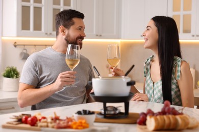 Photo of Romantic date with fondue. Couple with glasses of wine at home