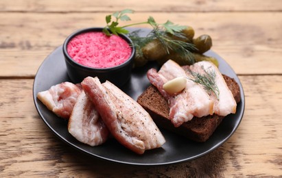 Photo of Pork fatback with rye bread and ingredients on wooden table, closeup