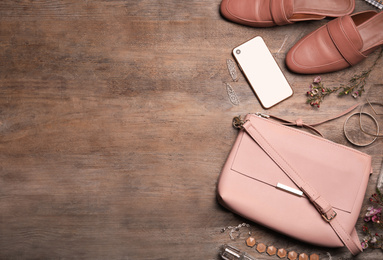 Flat lay composition with stylish shoes, small woman's bag and smartphone on wooden background. Space for text