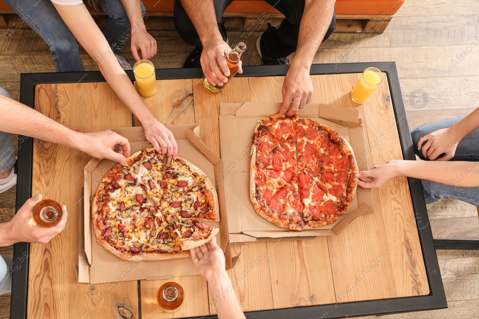 Photo of Young people eating delicious pizza at table, top view