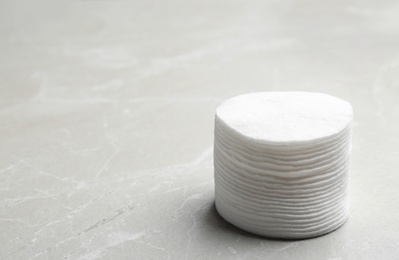 Stack of cotton pads on grey background. Space for text