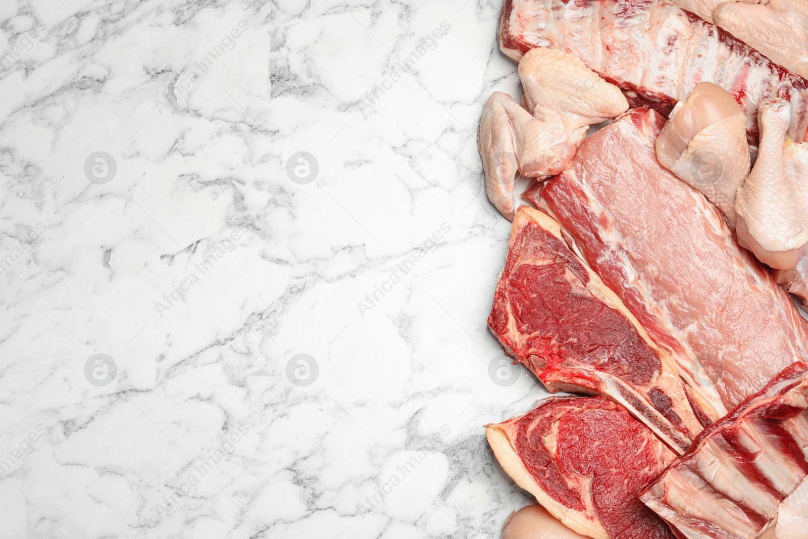 Photo of Different types of fresh raw meat on white marble table, flat lay. Space for text