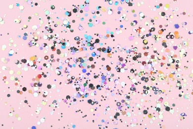 Photo of Shiny glitter on light pink background, top view