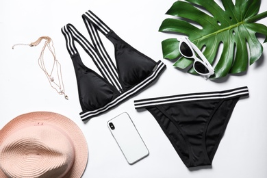Photo of Flat lay composition with bikini, smartphone and accessories on white background